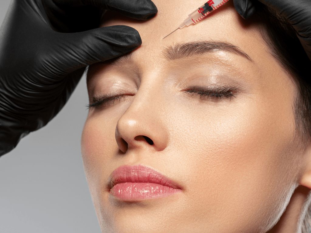 women with eyes closed get an injection in the forehead for wrinkles