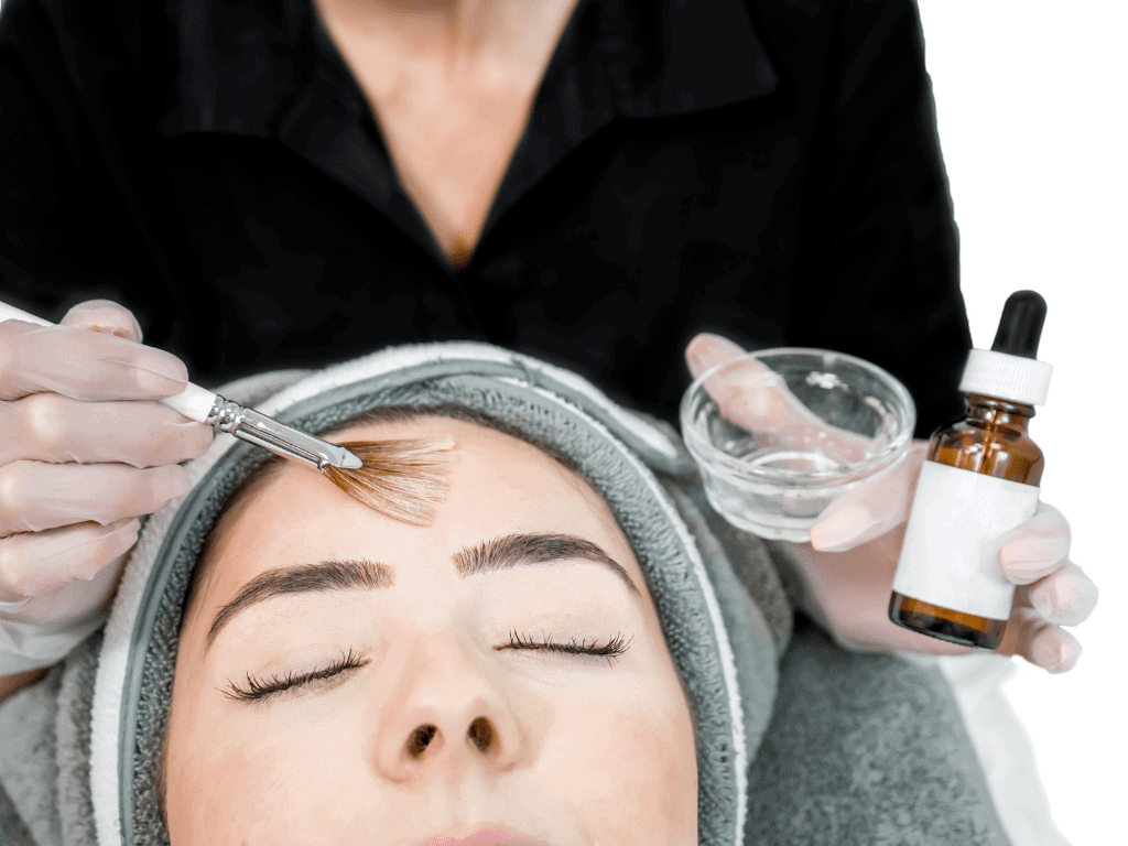woman with a towel on her head getting a chemical peel for rosacea with a face brush